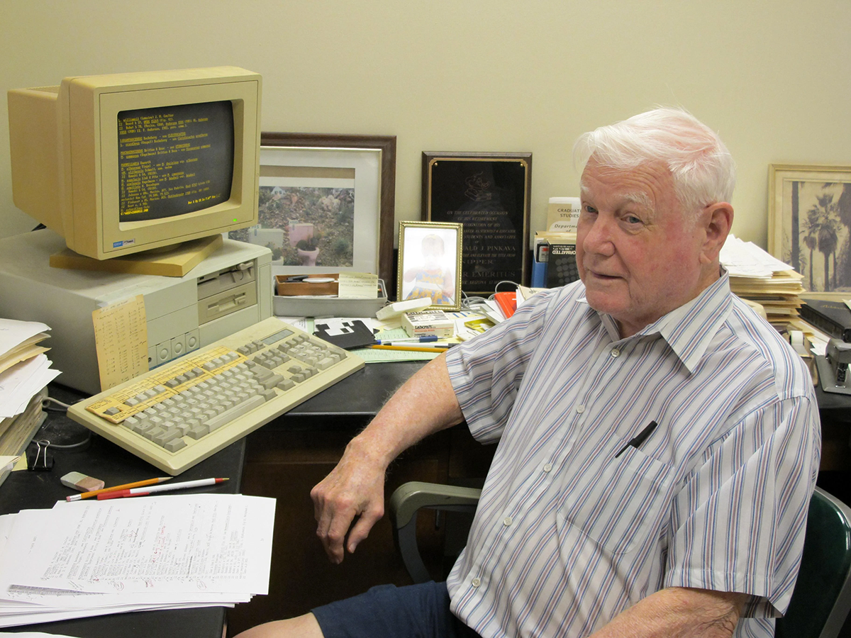 Elderly gentleman wearing striped shirt in front of an old computer